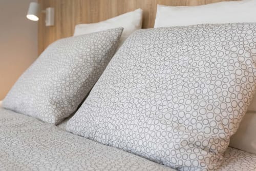 Gros plan sur le lit avec oreillers à motifs et couette dans l'appartement Un Air De Famille à Vittel