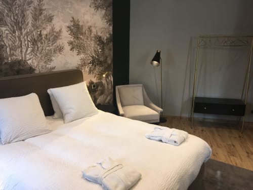 Modern bedroom at Le château d'Hermonville with white bed, decorative wallpaper, armchair, and wooden floors in Hermonville,