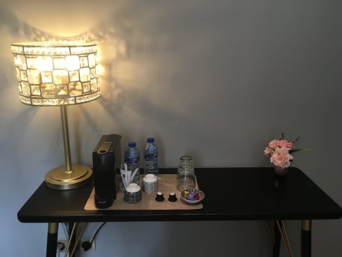 Elegant bedside table at Le château d'Hermonville with decorative lamp, water bottles, and pink flowers in superior double