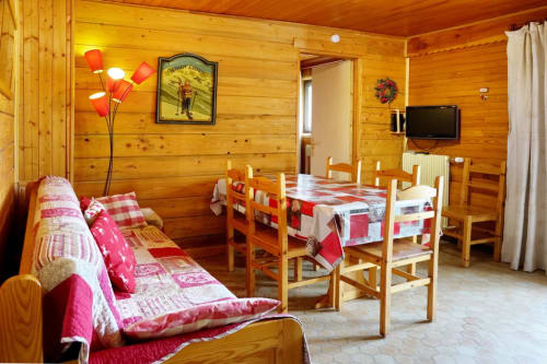 Chambre chaleureuse du chalet La Louvière avec lits jumeaux, table à manger, TV et décor rustique à Fontcouverte