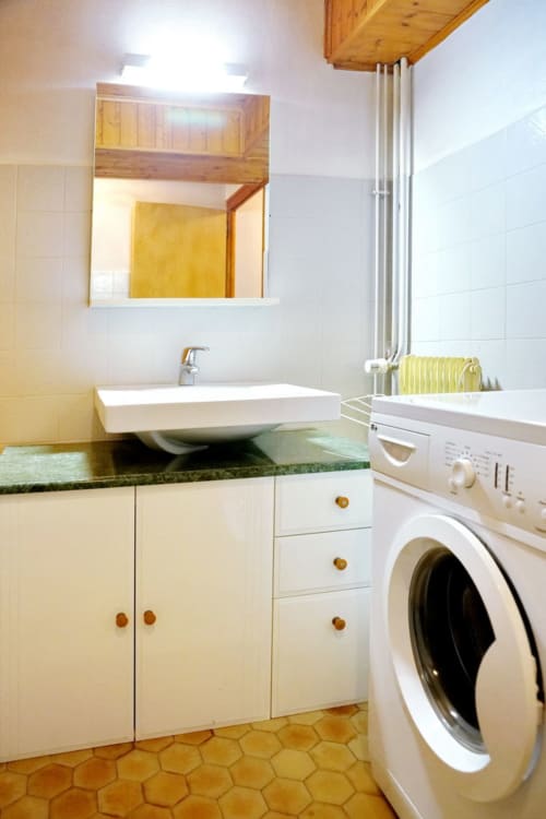 Modern bathroom at Chalet La Louvière with white sink vanity, washing machine, and heated towel rack in Petit Loup room