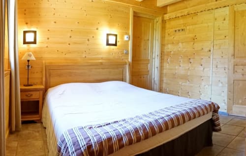 Chambre chaleureuse au Chalet La Louvière avec boiseries, lit queen-size, lampe de chevet et équipements modernes à Fontcouverte-La