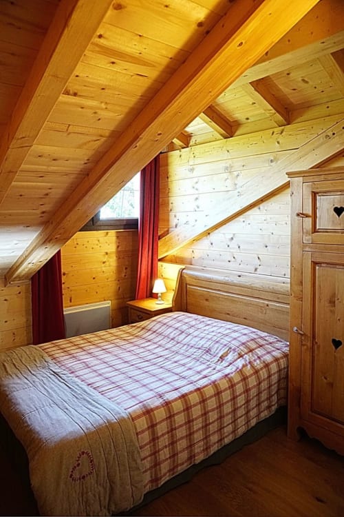 Chambre chaleureuse au Chalet La Louvière avec plafond mansardé, linge écossais, vue montagne et bois rustique