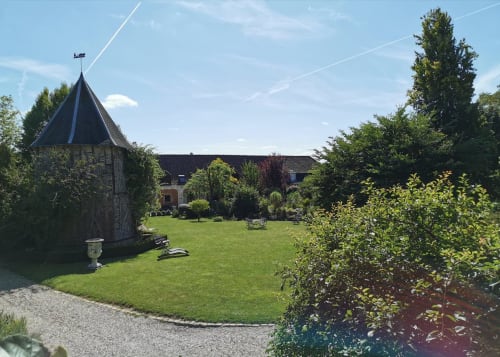 Élégante cour intérieure de La Cour d'Hortense avec tour lierre, pelouse soignée et bâtiments manoriaux français