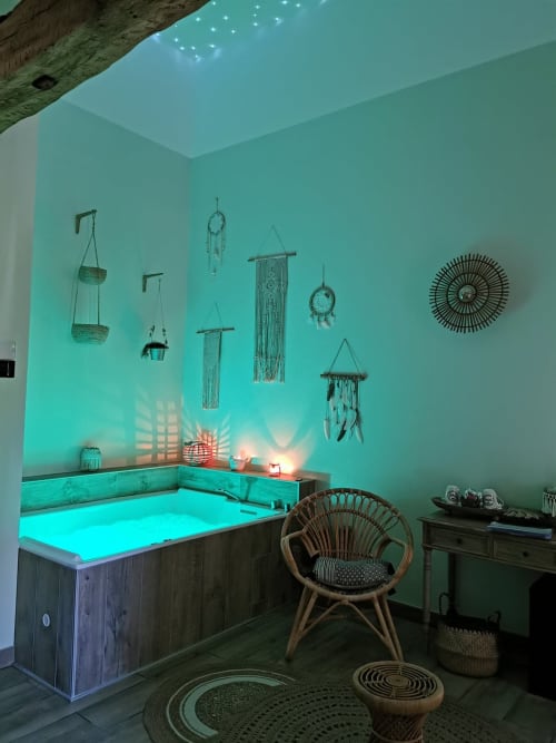 Spa turquoise à La Cour d'Hortense avec baignoire lumineuse, décor bohème, attrape-rêves et chaise en rotin