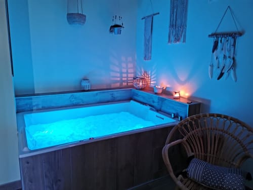 Bain à remous privé aux eaux bleutées lumineuses, décoration en macramé suspendue et chaise en rotin à La Cour d'Hortense