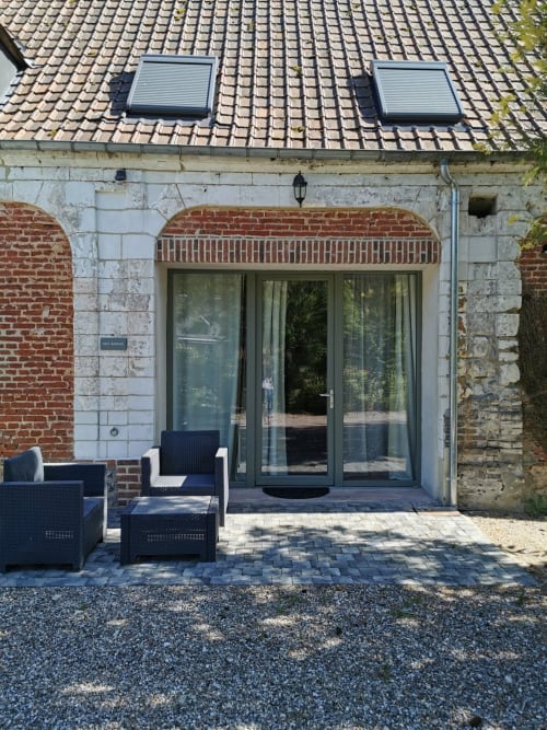 Vue sur le jardin de la terrasse de La Cour d'Hortense à Sailly-Flibeaucourt avec salon extérieur et portes vitrées modernes
