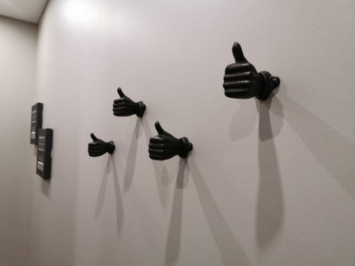 Sculptures de mains pouces levés en noir fixées sur mur blanc au gîte La Cour d'Hortense en France