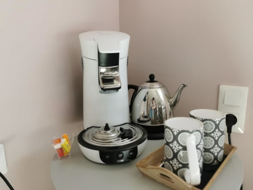 Station de café et thé en chambre avec bouilloire, cafetière et tasses à motifs à La Cour d'Hortense B&B