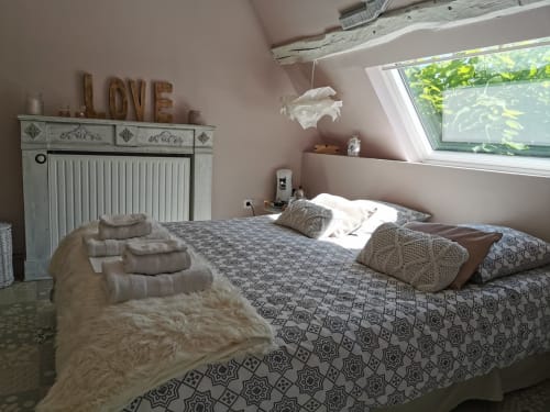 Chambre douillette à La Cour d'Hortense avec literie motifs, puits de lumière, commode vintage et panneau LOVE, vue sur jardin