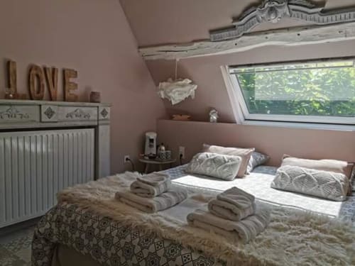 Chambre accueillante à La Cour d'Hortense B&B à Sailly-Flibeaucourt avec murs roses, vue sur le jardin et serviettes soigneusement pliées