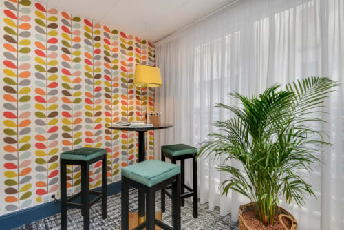 Colorful leaf-patterned accent wall with seating area and green plant at Hotel Residence Europe & Spa in Clichy