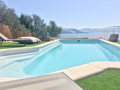 Luxury pool at Villas Marincelu in Porto Pollo with turquoise water, lounge chairs, lake view and mountains