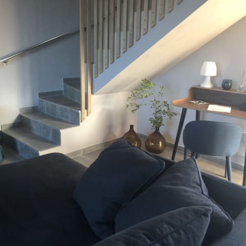 Intérieur loft moderne aux Villas Marincelu avec escalier, canapé foncé, bureau en bois et lumière naturelle