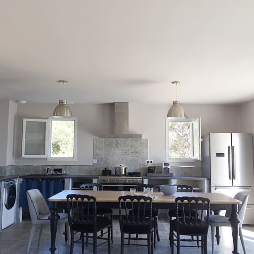 Cuisine moderne et salle à manger aux Villas Marincelu avec chaises noires, électroménagers en acier inoxydable et lumière naturelle