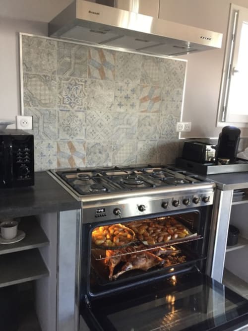 Cuisine moderne à Villas Marincelu avec cuisinière inox, dosseret en carreaux à motifs et viandes rôties au four