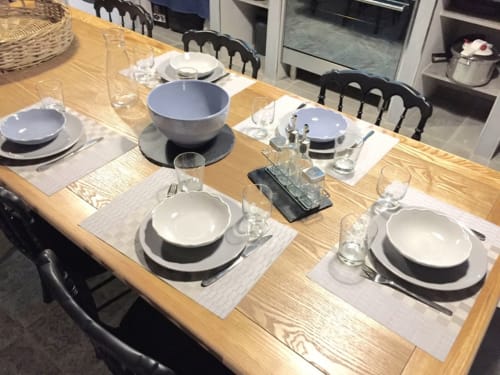 Table de salle à manger élégante aux Villas Marincelu avec couverts, assiettes blanches, verres et chaises foncées.