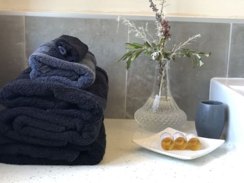 Bathroom spa setup at Villas Marincelu with rolled towels, fresh flowers, toiletries on white dish, and dark ceramic cup