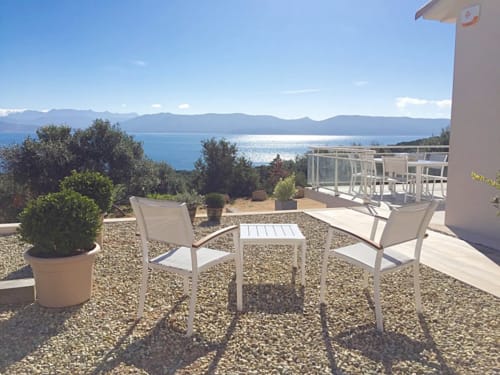 Seaside terrace at Villas Marincelu with white loungers overlooking turquoise Mediterranean Sea near Serra di Ferro, Corsica