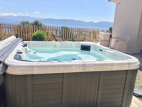 Luxury hot tub at Villas Marincelu with turquoise water, mountain views, and wooden deck in Corsica