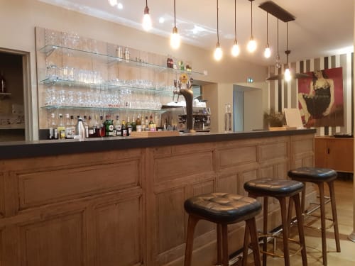 Le bar de l'hôtel Les Cabines à Houlgate avec comptoir en bois, luminaires suspendus et places assises au bar