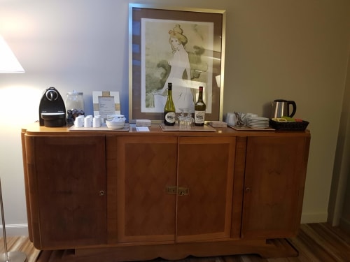 Station de boissons de l'hôtel aux Cabines Houlgate avec cafetière, bouteilles de vin et portrait vintage