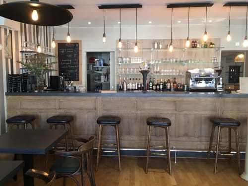 Bar moderne de l'hôtel Les Cabines à Houlgate avec suspensions, comptoir en bois et cinq tabourets