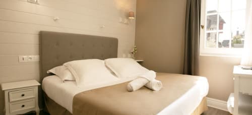 Chambre spacieuse beige aux Cabines à Houlgate avec lits jumeaux, tête de lit capitonnée et lumière naturelle
