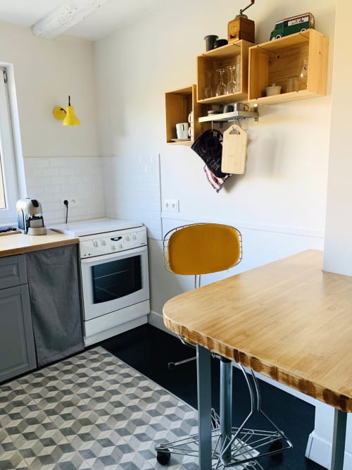 Cozy kitchen at l'Atelier des Dépendances in Lipsheim with wooden shelving, dining table, and yellow chair