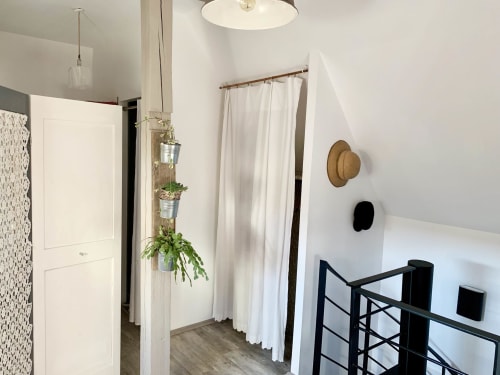 Modern bedroom at l'Atelier des Dépendances BnB in Lipsheim with white walls, hanging plants, and black metal railing detail.