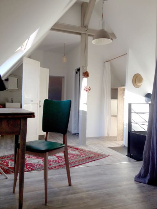 Spacious attic room at l'Atelier des Dépendances with green chair, red rug, and modern lighting