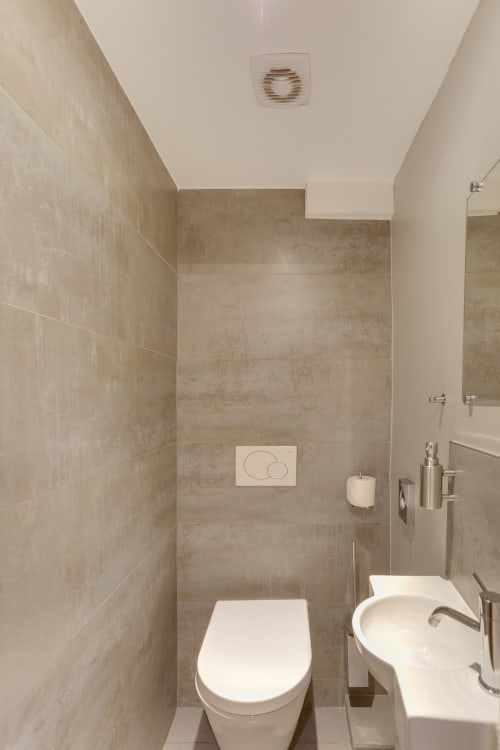 Salle de bain moderne de la suite Deluxe de l'Hôtel Louvre Richelieu Paris avec toilettes, lavabo et carrelage beige