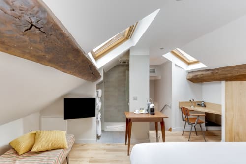 Chambre déluxe à l'Hôtel Louvre Richelieu Paris avec poutres apparentes, verrière, bureau et équipements modernes