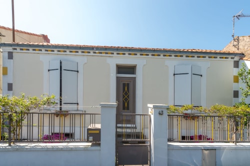 Façade extérieure de la maison d'hôtes L'escale Marine à La Rochelle avec sa devanture blanche, volets bleus et détails de garniture jaune
