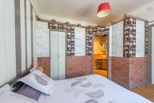 Chambre Anis de L'escale Marine B&B à La Rochelle : mur de briques, rangements intégrés et luminaire rouge