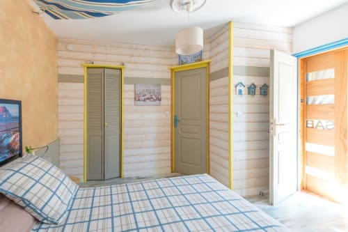 Chambre lumineuse à L'escale Marine B&B à La Rochelle, portes jaunes, literie rayée et murs en bois clair
