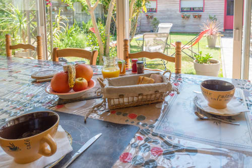 Petit-déjeuner à L'escale Marine à La Rochelle avec tasses de café, fruits frais et vue sur la terrasse du jardin