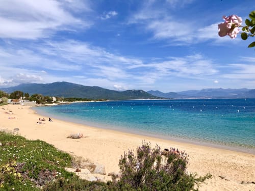 Playa virgen de arena fina en Villas Marincelu, Porto Pollo, Córcega, con aguas turquesas y costa montañosa
