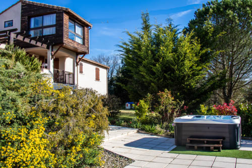 Belloréade B&B in Belloc features a modern elevated wooden structure with hot tub and gardens under blue sky