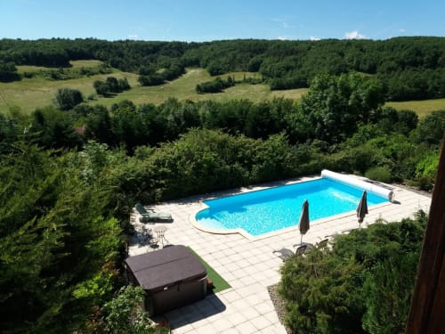 Belloréade's private swimming pool surrounded by lush green countryside near Belloc, France with mountain views