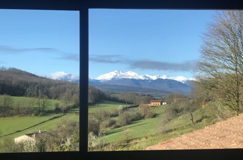 Snow-capped Pyrenees mountain view from Belloréade room in Belloc, France with rolling green valleys and countryside