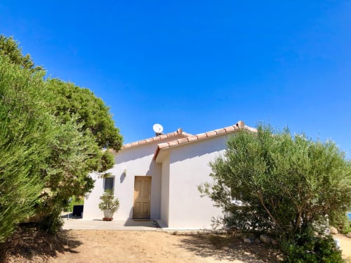 White Mediterranean villa at Villas Marincelu with terracotta roof, surrounded by green vegetation under clear blue sky