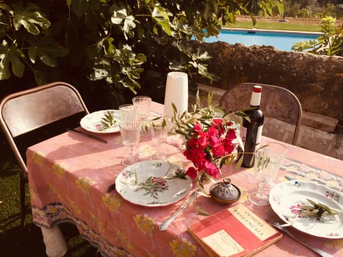 Elegant outdoor dining setup at Saint Martin B&B in Ollioules with pink tablecloth, red flowers, wine bottle, and pool view