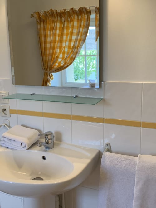 Modernes Waschbecken mit Spiegel und goldenem karierten Vorhang im La Croix De La Jarrie B&B in Châtres