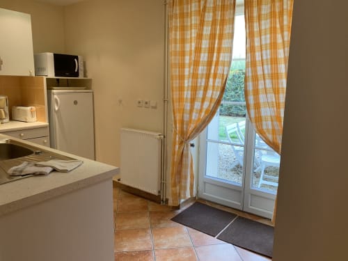 Küche mit Essbereich, ausgestattet mit Mikrowelle und Kühlschrank, mit Blick auf den Garten in La Croix De La Jarrie