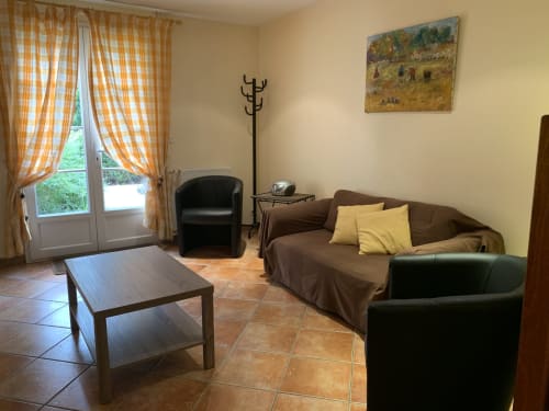 Séjour lumineux à La Croix De La Jarrie avec canapé marron, fauteuils, table basse et vue sur le jardin
