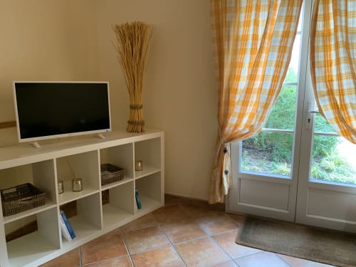 Helles Wohnzimmer mit Flachbildfernseher auf Regaleinheit, orangekarierten Vorhängen und Gartenblick in La Croix De La Jarrie, Châtres