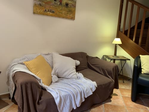 Gemütliches Wohnzimmer mit braunem Sofa, gelb-weißen Kissen und blauer Decke im Gästehaus La Croix De La Jarrie in Châtres