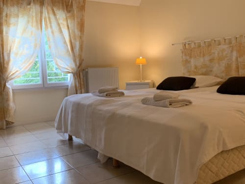 Helles Schlafzimmer mit zwei Betten, schwarzen Kissen, aufgerollten Handtüchern, Lampe und Fenster mit Gartenblick im La Croix De La Jarrie in Châtres