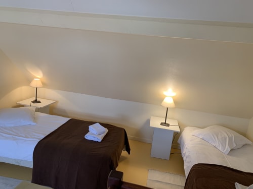Gemütliches Schlafzimmer im La Croix De La Jarrie BnB mit Einzelbetten, Nachttischlampen und Schrägedach in Châtres